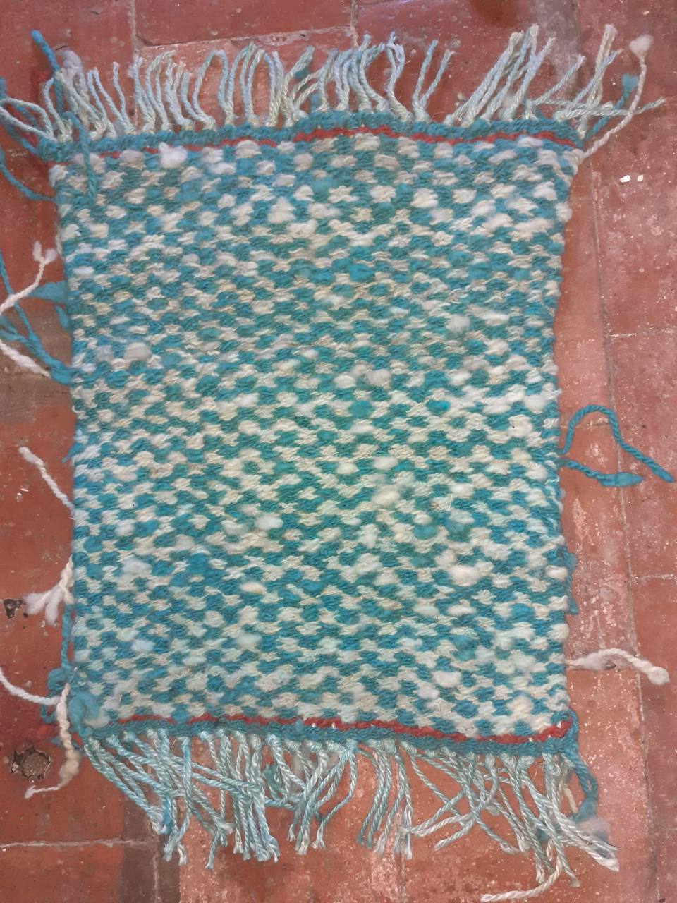 Turquoise and white handwoven rug with fringe